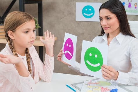 smiling-psychologist-showing-happy-sad-emotion-faces-cards-girl-child